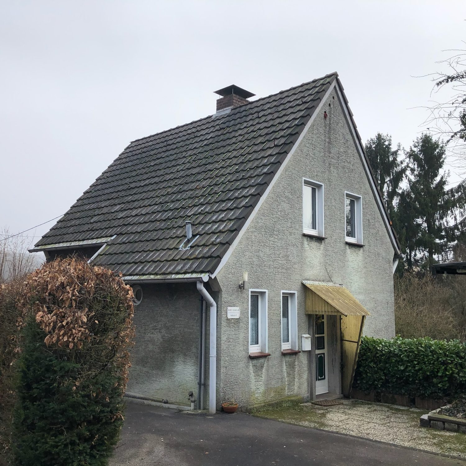 Projekt H9 Zweistöckiges graues Haus mit Satteldach und auffälligem Vordach.