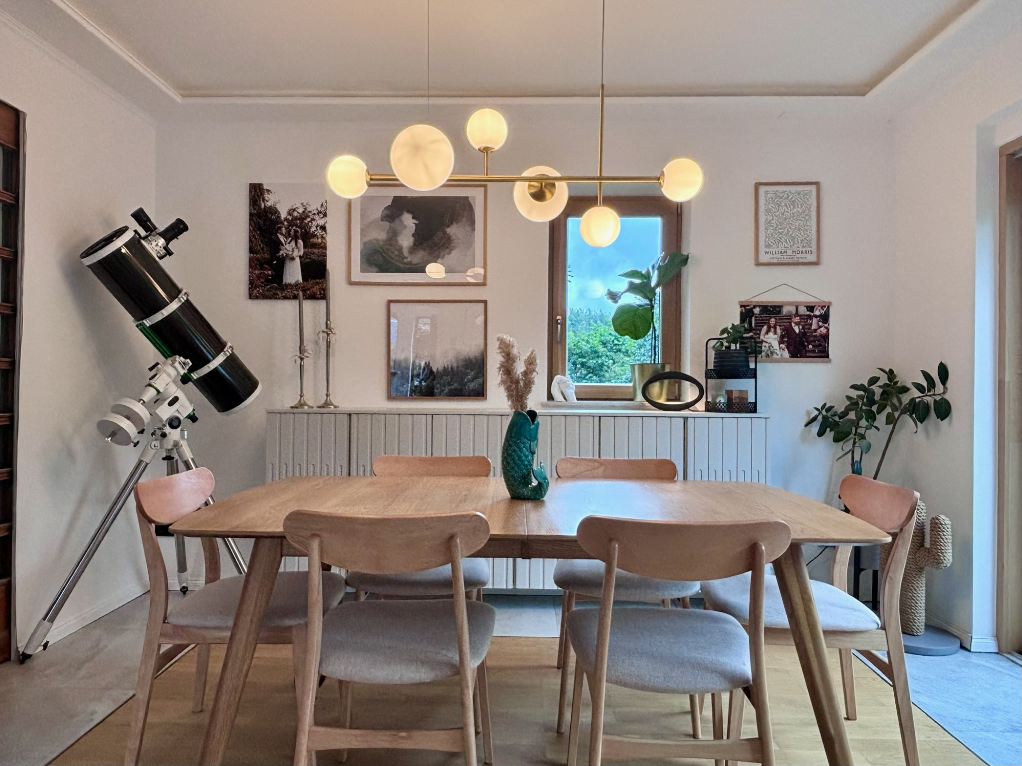 Esszimmer Moderner Essbereich mit Holztisch, Stühlen, Pflanzen und Teleskop in gemütlicher Atmosphäre.