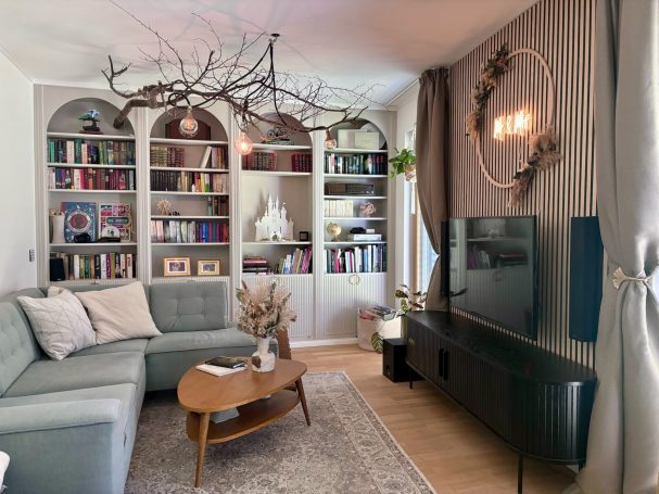 Helles Wohnzimmer mit Sofa, Bücherregal und moderner Dekoration.