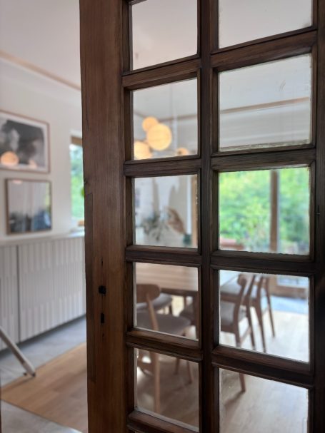 Blick durch eine Glastür auf einen Essbereich mit einem Tisch und Stühlen.