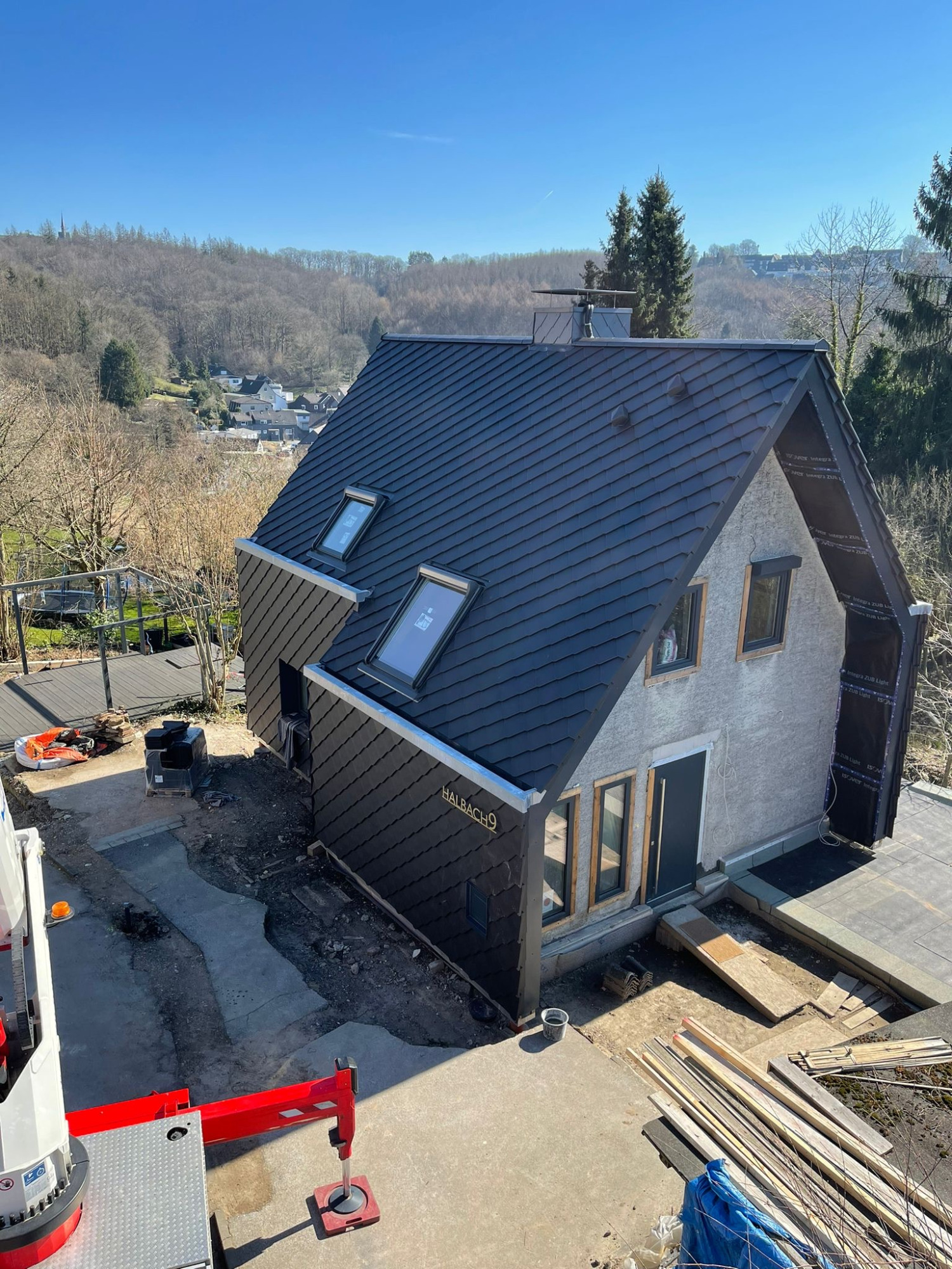 Fassadenerneuerung Einfamilienhaus mit modernen Fenstern, umgeben von Natur, im Bauzustand.