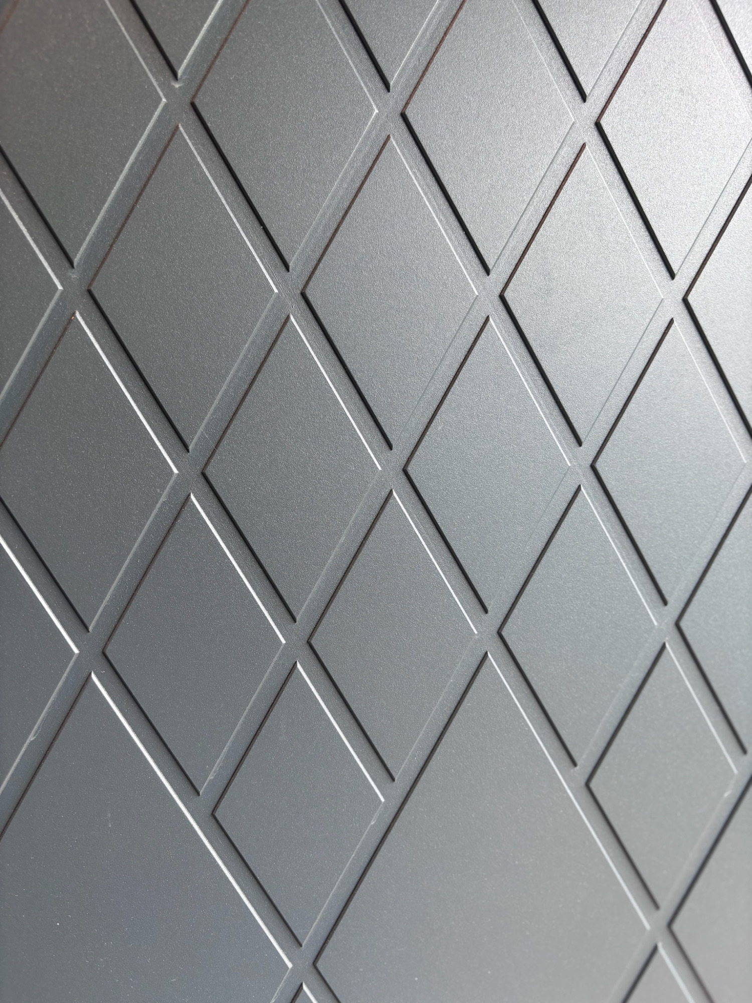 Detail Haustür Grau marmorierte Oberfläche mit diagonalen Rautenmuster in regelmäßigen Abständen.