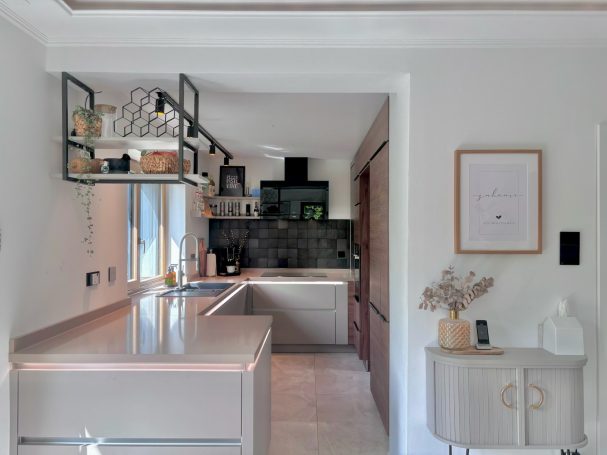 Moderner Küchenbereich mit grauen Wänden, Holzdetails und eleganten Geräten.