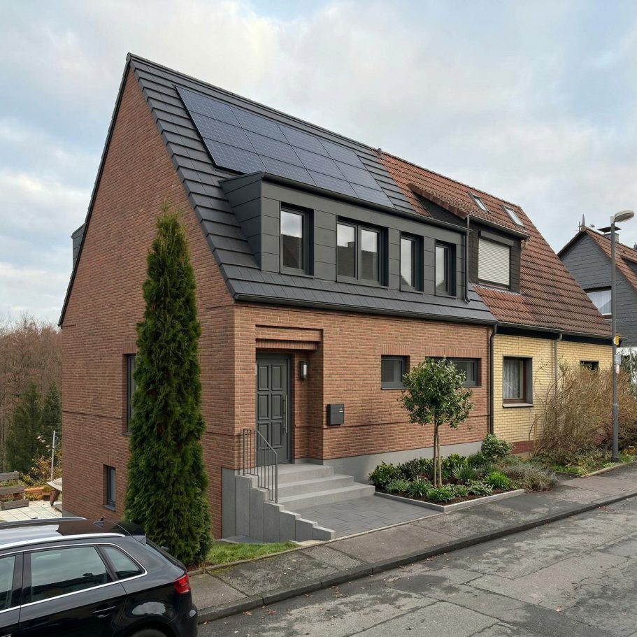 Visualisierung (KI-generiert) Modernes Haus mit Solarpanelen, grüner Pflanze und Auffahrt, in ruhiger Wohngegend.