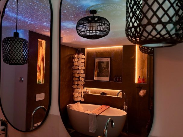 Badezimmer mit freistehender Badewanne, stilvollen Lampen und stimmungsvollem Licht.