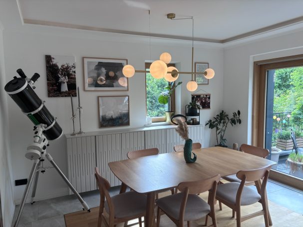 Ein heller Essbereich mit einem Tisch, Stühlen und einem Teleskop in der Ecke.