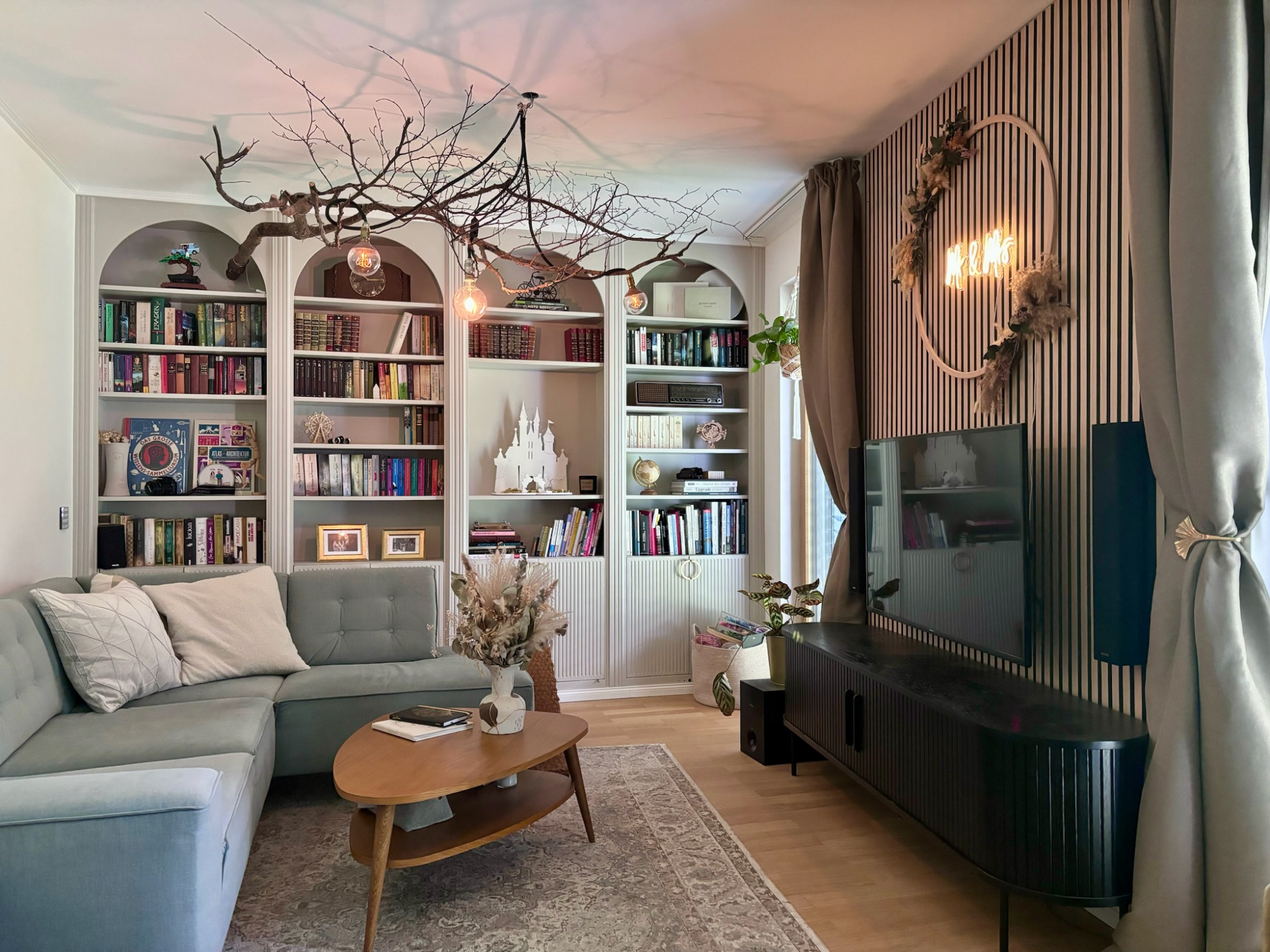 Wohnzimmer Moderner Wohnraum mit grauem Sofa, Bücherregal und stilvollen Dekorationselementen.